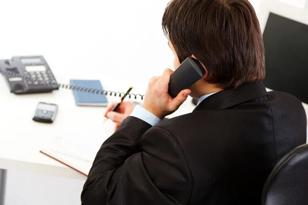 Homme d'affaires au bureau parlant au téléphone et prenant des notes dans son journal intime — Photo