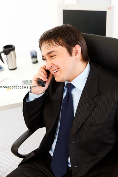Lachende jonge zakenman praten op telefoon in office — Stockfoto