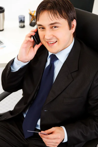 Empresário sorridente no escritório fazendo compra por telefone e cartão de crédito — Fotografia de Stock