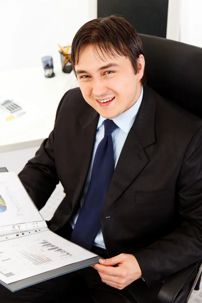 Usmívající se podnikatel, sedí v kanceláři a práci s finanční docu — Stock fotografie