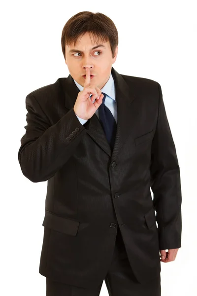 Alerta a hombre de negocios con el dedo en la boca y mirando en la esquina. Shh gesto — Foto de Stock