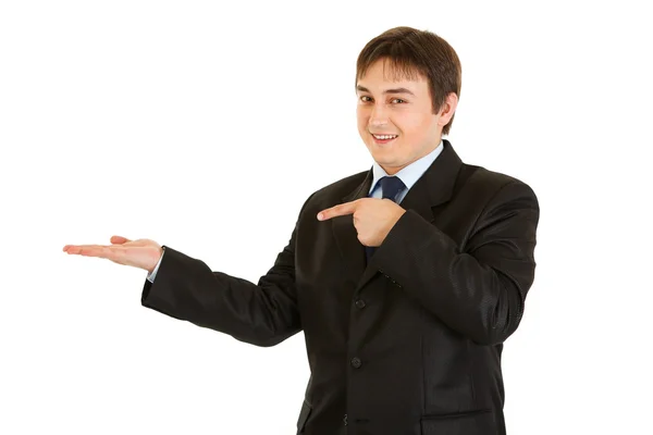 Smiling young businessman pointing finger on empty hand — Stock Photo, Image