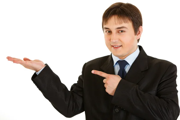 Smiling young businessman pointing finger on empty hand — Stock Photo, Image