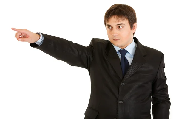 Serious young businessman pointing finger in corner — Stock Photo, Image