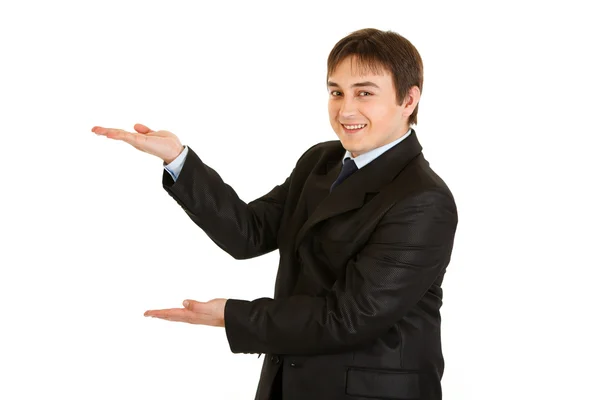 Friendly young businessman presenting something on empty hands — Stock Photo, Image