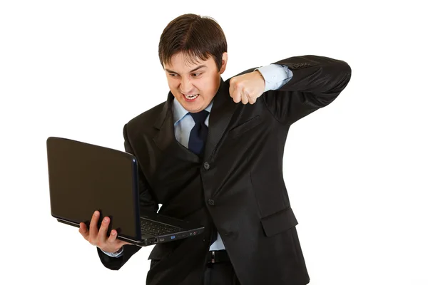 Angry young businessman trying to hit laptop — Stock Photo, Image