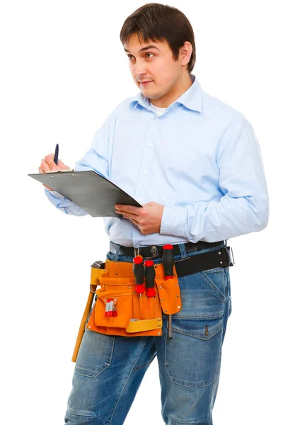 Robotnik budowlany, sprawdzanie czegoś i pisanie w schowku — Zdjęcie stockowe