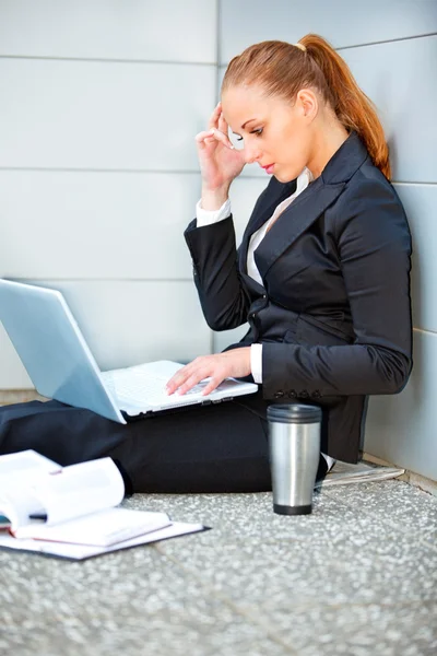 stock image Concentrated business woman sitting on floor at office building and using