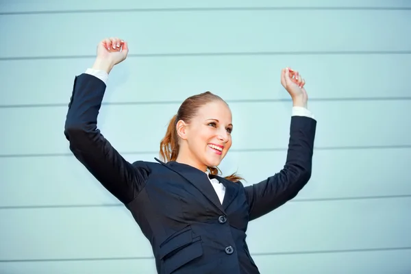 Возбужденная деловая женщина, стоящая у офисного здания и радующаяся своей соске — стоковое фото