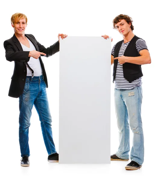 Dois jovens modernos apontando em cartaz em branco. Isolado no wh — Fotografia de Stock