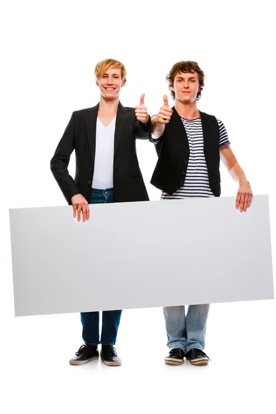 Два веселых молодых человека держат пустой рекламный щит и показывают большой палец — стоковое фото
