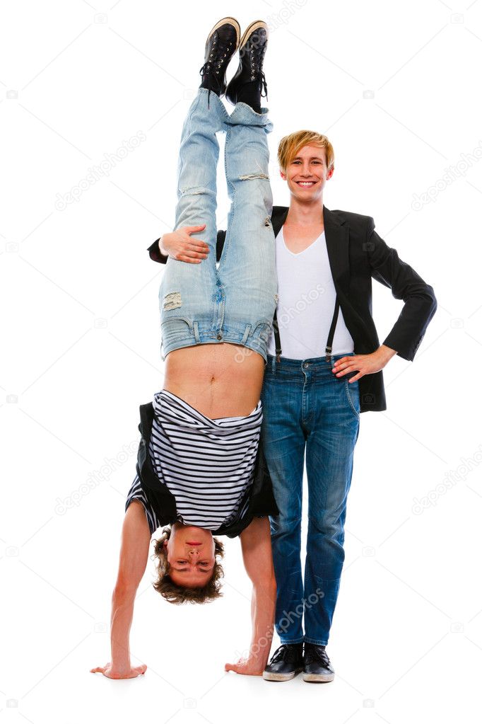 Young man holding his standing upside down friend. Isolated on w