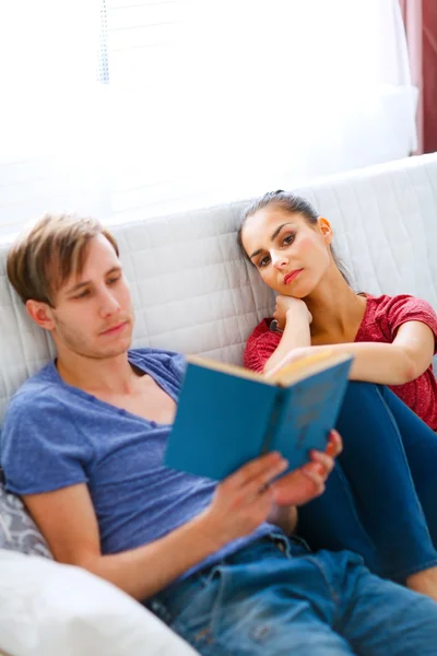 Girl boring while her boyfriend reading book — Stock Photo, Image