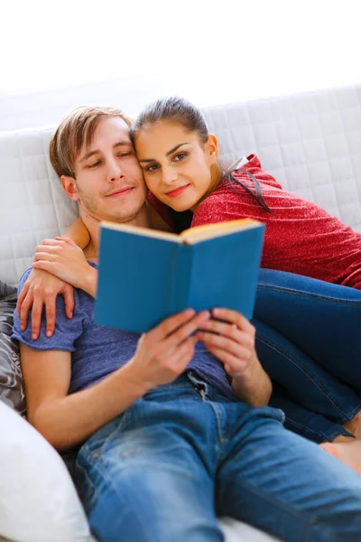 Романтическая пара, сидящая на диване и читающая книгу — стоковое фото