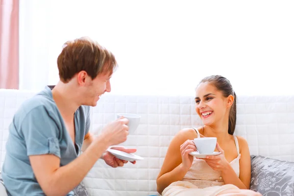 Młoda para siedzi na kanapie i picia kawy — Zdjęcie stockowe