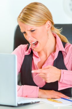 mujer de negocios enojado sentado en el escritorio de oficina y de la mano junto a la cabeza