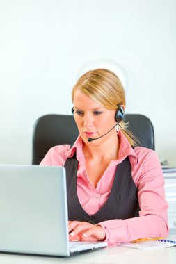 Modern business woman with headset working on laptop clipart