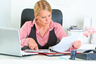 Concentrated business woman sitting at office desk clipart