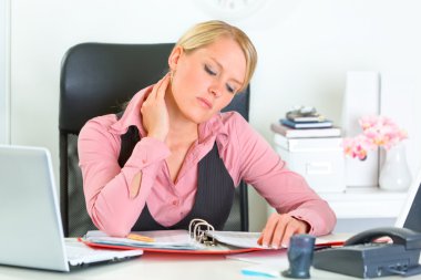 Tired business woman sitting at office desk and working clipart