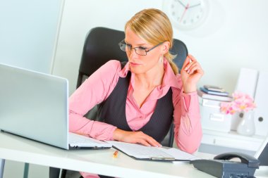 Modern business woman in eye glasses working on laptop clipart