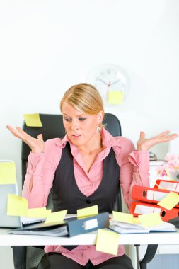 Shocked by set of tasks business woman sitting at workplace covered with st clipart