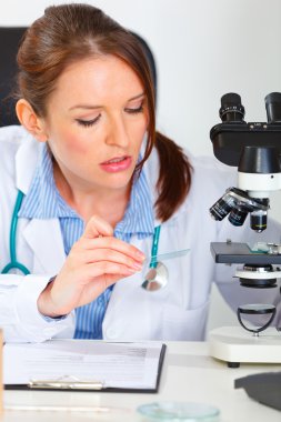 Busy female medical doctor working sample in laboratory clipart