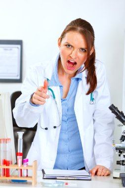 Angry doctor woman shouting and pointing on you clipart