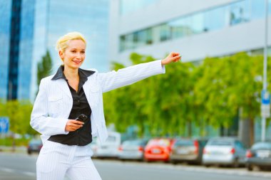 Smiling business woman catching taxi near office center