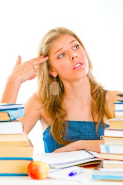 Stressful teen girl sitting at table with books and holding gun shaped hand clipart