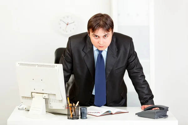Estrito homem de negócios moderno em pé na mesa de escritório — Fotografia de Stock