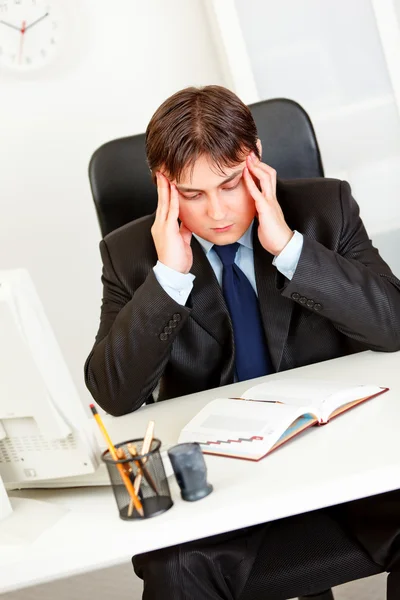 Zakenman achter bureau houdt zijn hoofd en verontrustend benadrukt — Stockfoto