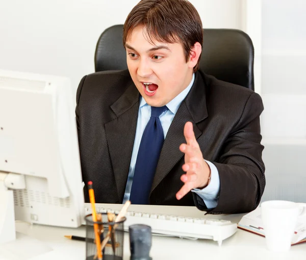 Σοκαρισμένος επιχειρηματία που κάθεται στο γραφείο και κοιτάζοντας οθόνη υπολογιστή — Φωτογραφία Αρχείου