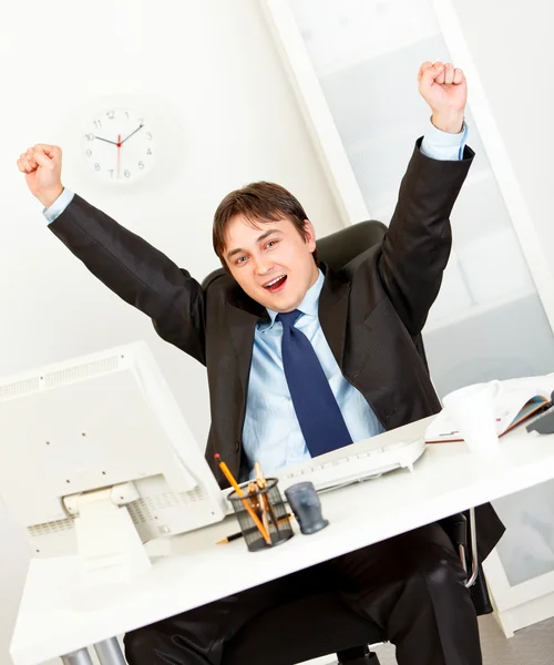 Nadšený podnikatel, sedí v kanceláři a raduje jeho úspěchu — Stock fotografie