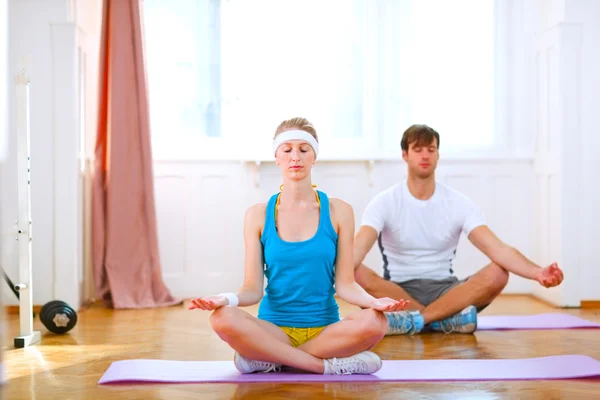 Young man and fit woman doing yoga at home — Stock Photo, Image