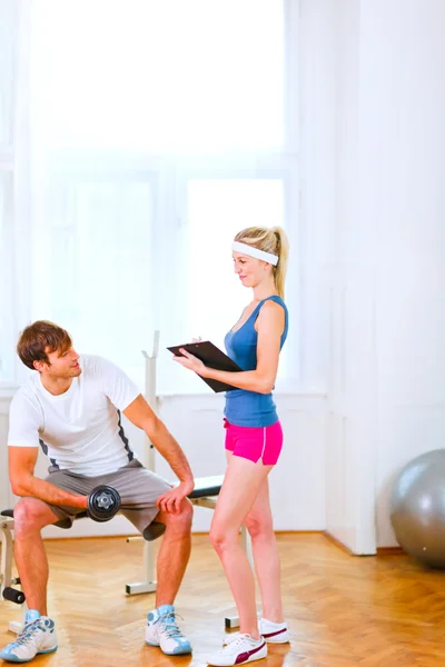Young man lifting a dumbbell under the supervision of personal t — Stock Photo, Image