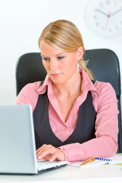 Femme d'affaires concentrée assise au bureau et travaillant sur un ordinateur portable — Photo