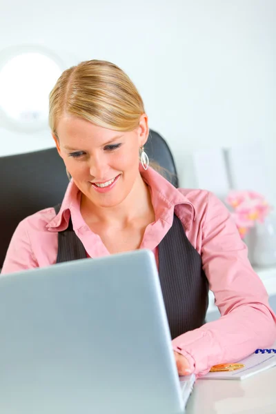 Улыбающаяся деловая женщина, работающая на ноутбуке в офисе — стоковое фото