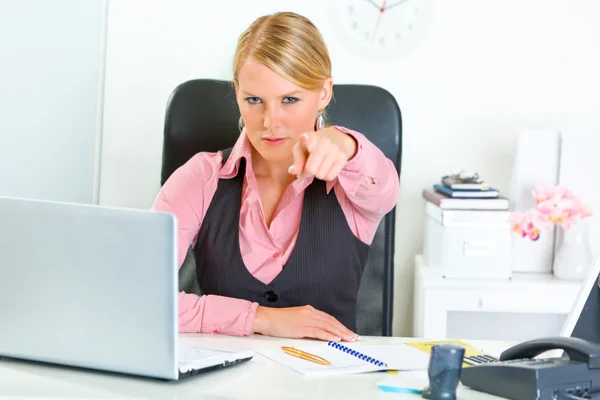 Confident business woman sitting at office desk and pointing finger at you — Stock Photo, Image