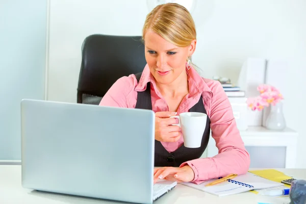Donna d'affari felice che lavora su computer portatile e beve caffè — Foto Stock