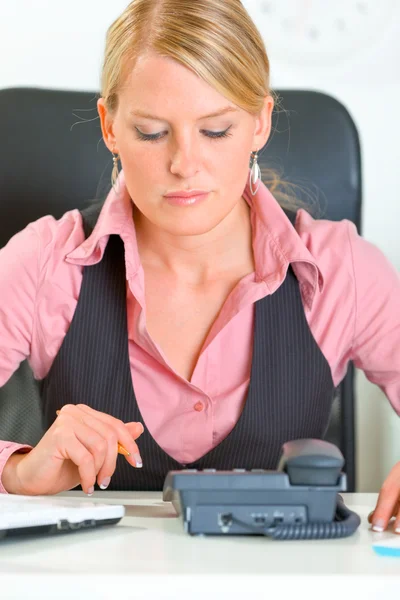 Mujer de negocios concentrada sentada en el escritorio de la oficina y esperando una llamada telefónica —  Fotos de Stock
