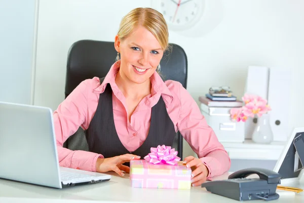 Happy modern business woman with present box at office desk — Stock Photo, Image