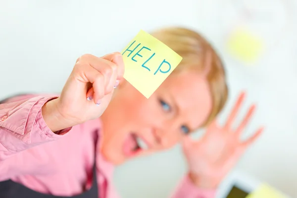 Stressed business woman showing sticky note with help word — Stock Photo, Image