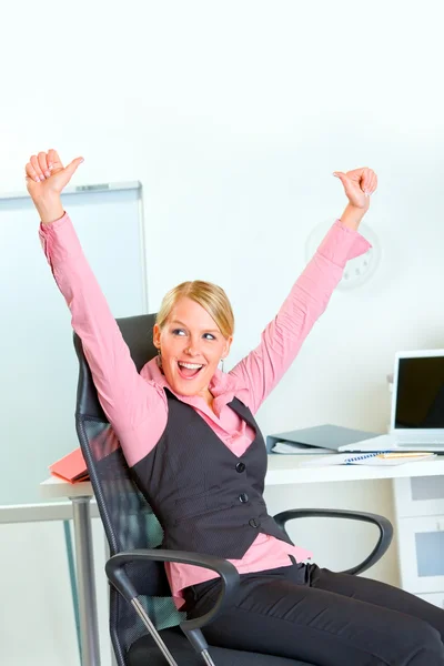 Щаслива бізнес-леді сидить на робочому місці радіючи успіху — стокове фото