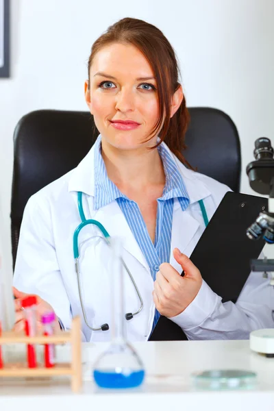 Retrato de médico feminino sentado no armário com clipbo — Fotografia de Stock