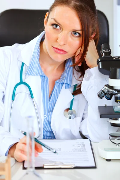 Thoughtful medical doctor woman sitting at office table — Stock Photo, Image