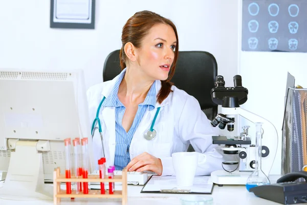 Kobieta lekarz siedzi przy stole biuro i odwracając — Zdjęcie stockowe