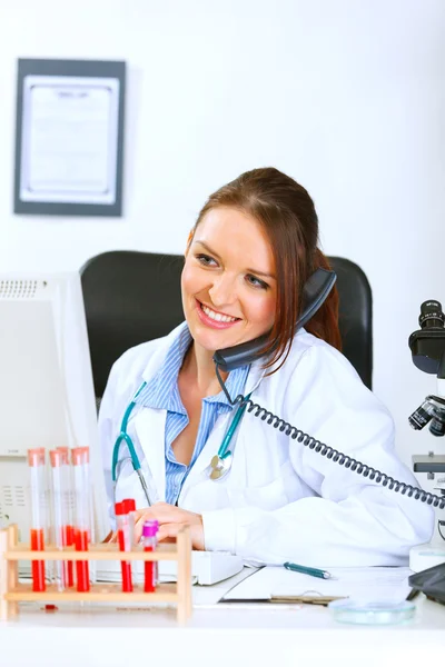 Smiling doctor woman talking on phone and looking in monitor — Stock Photo, Image
