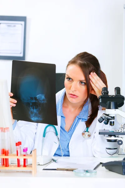Koncentrovaný doktor žena sedí u stolu v kanceláři a analyzování pacientů ro — Stock fotografie