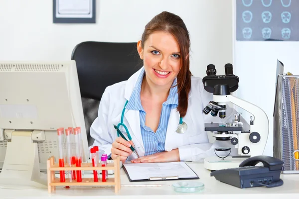Smiling female medical doctor working with documents at office — Stock Photo, Image