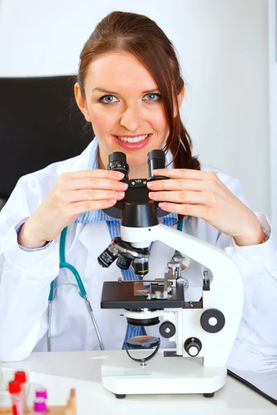 Médica sorridente usando microscópio — Fotografia de Stock